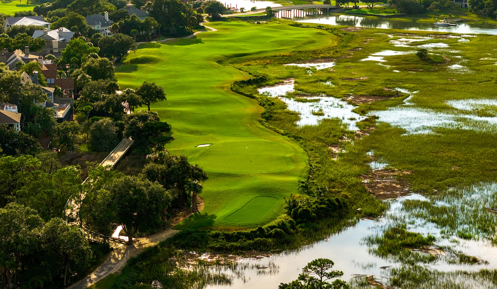 17th hole Harbor Course aerial — fairway hugging the marsh with bridge and harbor beyond